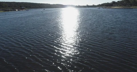 Low aerial flyover of sun reflection on rippling water in lake Stock Footage 100615362