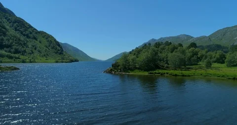Low aerial moving over surface of water skirting an island into Loch Schiel in Stock-Footage 115498985