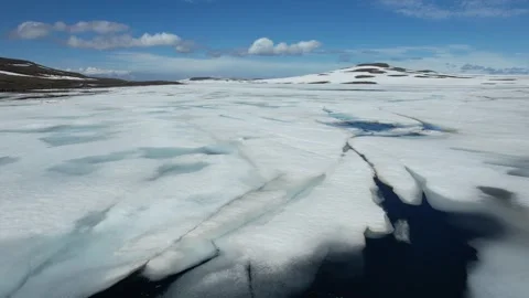 Low aerial over ice covered lake surface with cracks, Fjardarheidi Iceland Stock Footage 346551860