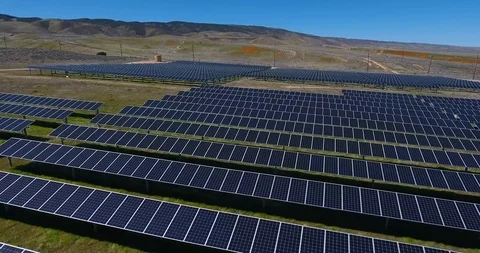 Low aerial over solar panel field with golden poppy wildflower covered mountains Stock Footage 104812539
