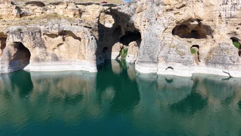Low Aerial Pullback from Cliff Caves Across Turquoise Lake Video stock 340127942