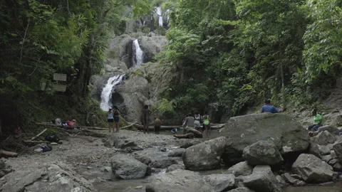 Low aerial pushes in to tourists bathing in Argyle Falls in Tobago Stock Footage 340852145