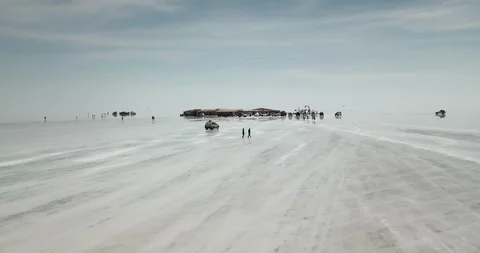 Low aerial sails over reflective surface of salt flats and salt hotel in Uyuni Vidéo 87487153