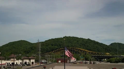 Low aerial of USA flag in front of Chuck Yeager Memorial Bridge in WV Stock Footage 310340429