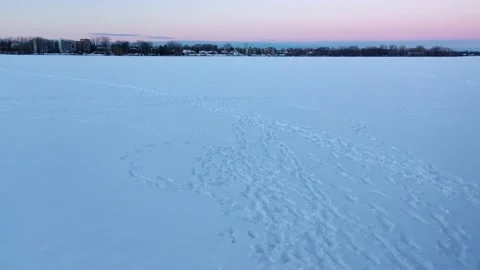 Low aerial view backing up over the frozen river showing the tracks in the sn Stock Footage 163981357