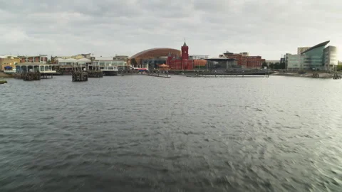 Low aerial view flying over water towards Cardiff Bay skyline Stock Footage 336810674