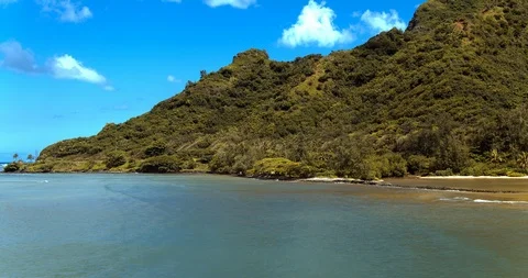 Low aerial view over tropical blue water flying towards lush jungle mountains Stock Footage 87945772