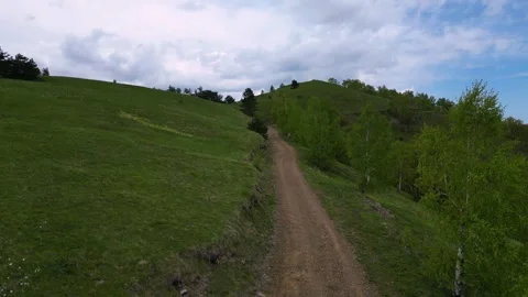 Low altitude aerial drone flight along dirt road through green hills Serbia Stock Footage 342241154
