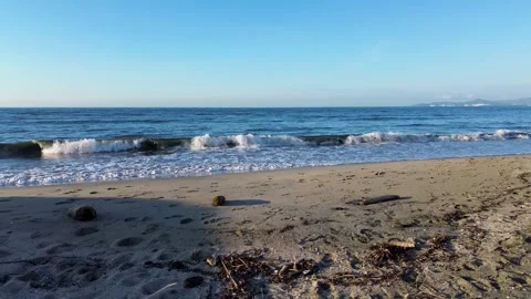 Low altitude drone flying from beach sand into the blue ocean waves, Cinematic Stock Footage 327097626