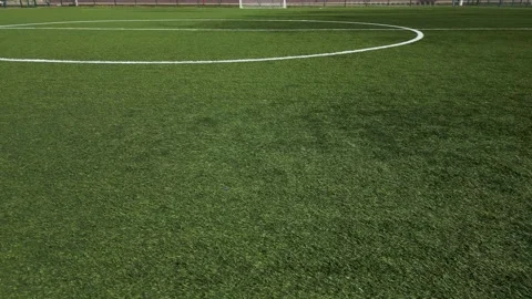 Low-altitude drone shot of an empty soccer field with artificial green grass Video stock 304451889