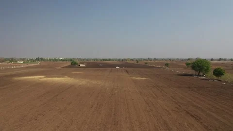 Low-altitude drone view of a dry agricultural patch showing faint tire tracks Stock Footage 337093225