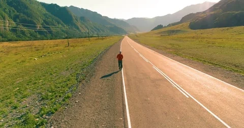 Low altitude flight behind of sporty man at perfect asphalt road Stock Footage