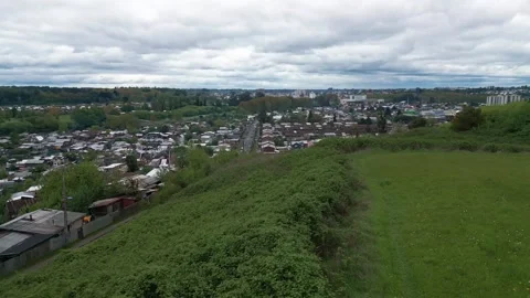 Low altitude flight over green hillside ravine revealing dense residential Stock-Footage 332609586