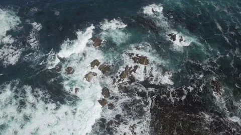Low Altitude moving drone shot of Pebble Beach shore with rocks and birds Stock Footage 64655823