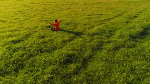 Low altitude radial flight over sport yoga man at perfect green grass. Sunset in Stock Footage 155080587
