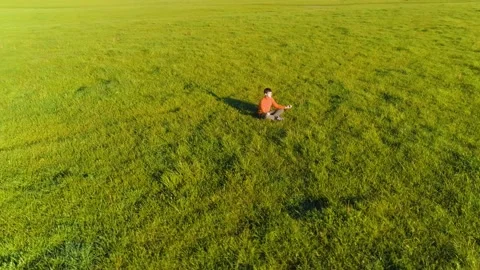 Low altitude radial flight over sport yoga man at perfect green grass. Sunset in Stock Footage 155083089
