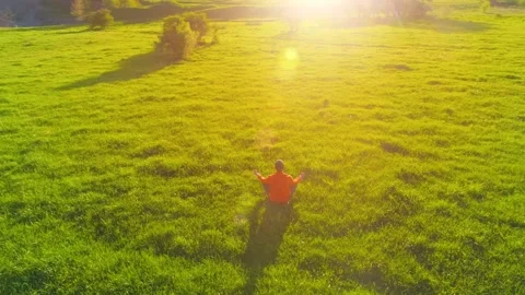 Low altitude radial flight over sport yoga man at perfect green grass. Sunset in Stock Footage 204932130