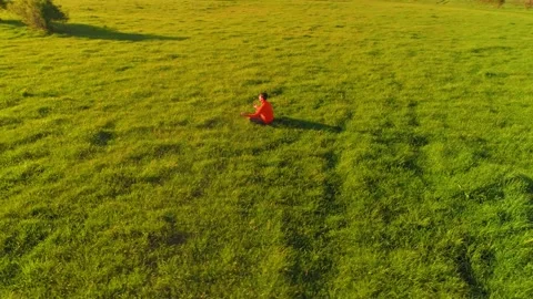 Low altitude radial flight over sport yoga man at perfect green grass. Sunset in Stock Footage 221686563