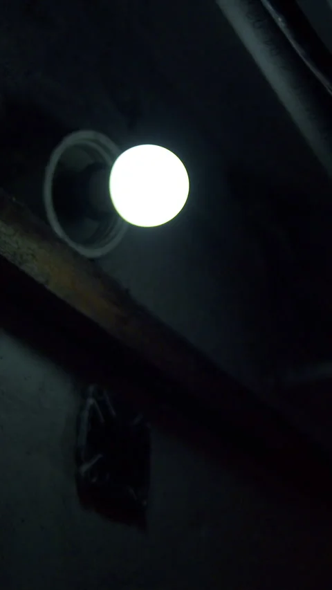 Low angle 4K of blinking white bulb in dark blue cellar Stock Footage 332633653