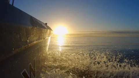 Low angle action cam view fishing boat heading out to sea toward sunrise Stock Footage 114715123