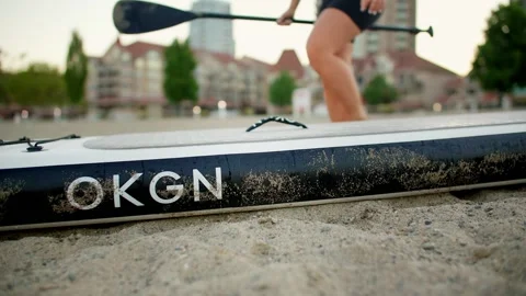 Low angle of adventurous girl picking up paddle board on city beach 库存影片 211733356