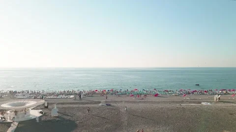 Low angle aerial panoramic fly over view of busy pebble beach in Batumi, Ge.. Stock-Footage 333442443