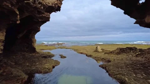 Low angle aerial pov push of coastal rock pool between rock features Stock-Footage 328625108