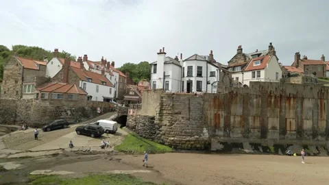 Low angle aerial of Robin Hoods Bay, Tourists on the beach Stock Footage 199658346