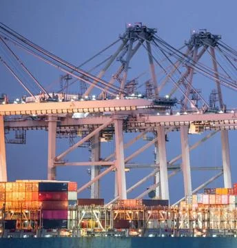 Low Angle Aerial Shot of Cranes Looming Over Container Ship Stock Photos