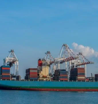 Low Angle Aerial Shot of Cranes Looming Over Container Ship Stock Photos