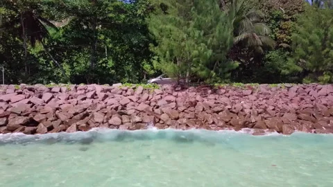 Low angle aerial: Tracking a car with waves breaking in the foreground Stock Footage 242016357