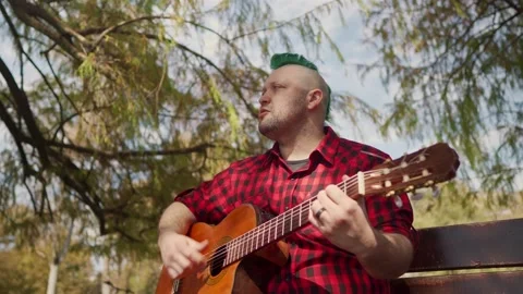 Low angle of an alternative man playing guitar and singing at park Stock-Footage 139274431