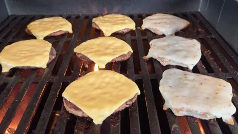 Low angle and close-up cheeseburgers and chicken burgers on hot grill with .. Stockbeeldmateriaal 337575340