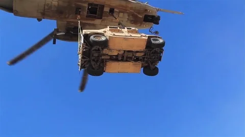 Low angle of an Armored Security Vehicle lifted by a Super Stallion helicopter Stock Footage 83466264