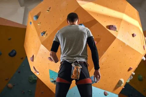 Low angle back view of physically impaired sportsman staring at climbing wall Stock Photos