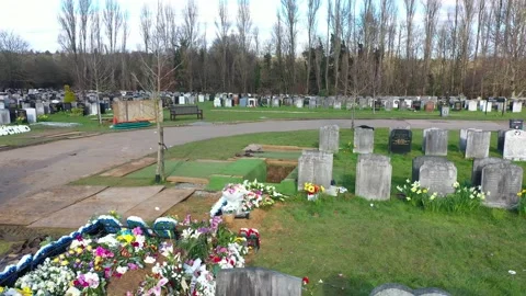 LOW ANGLE BACKDRS REVEAL OF CEMETERY WORKERS AND EMPTY GRAVE, AERIAL Video stock 150760749