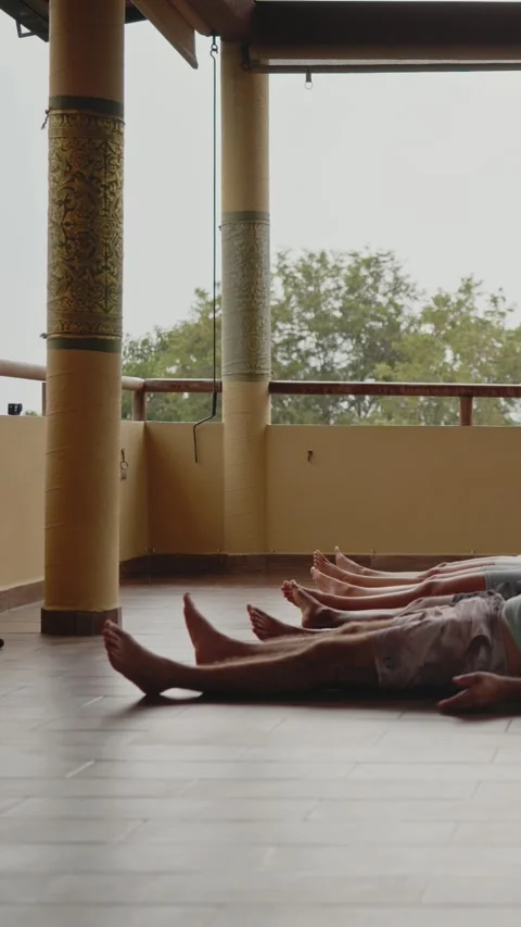 Low angle of bare feet and legs of students lying in savasana on wooden floor Stockbeeldmateriaal 347703307