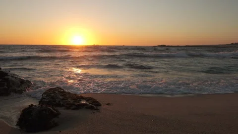 Low angle beach sunset with rocks in foreground Stock Footage 131888420