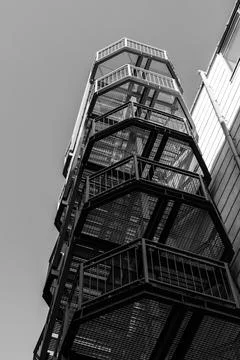 Low-angle black and white photo of a metal fire escape staircase Stock Photos