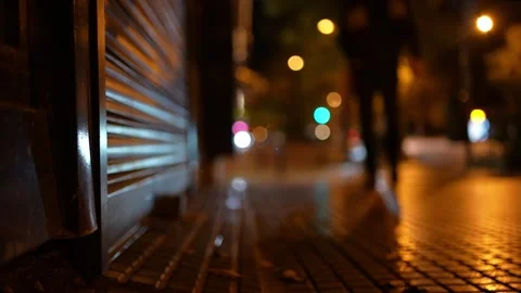 Low angle blurred video, a man getting closer and raising the shutter of a shop 스톡 동영상 244498974