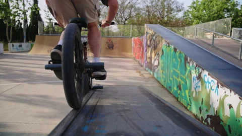 Low angle BMX rider enters frame rides ledge and jumps off ramp slow motion Stock Footage 337220647