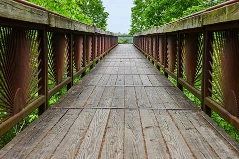 Low angle of bridge with setting sun pattern on railing and wooden walkway path 스톡 사진