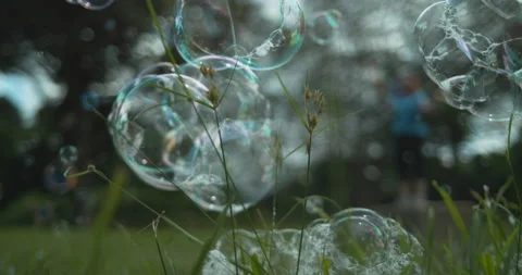 Low angle bubbles bursting as they hit the grass in super slow motion Stock Footage 154812994