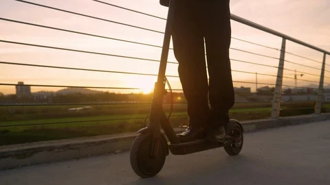 LOW ANGLE: Businessman rides an e-scooter to work on a sunny spring morning. Stock Footage 121732133