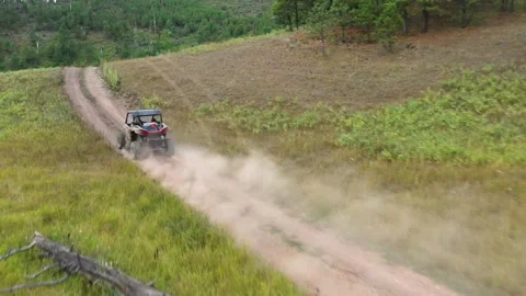 Low angle chasing drone shot of a 4x4 UTV, ATV, driving over a hill a Stock Footage 303064468