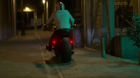 Low angle close up. Back wheel of a motorcycle before driving away at night Stock Footage 236090217