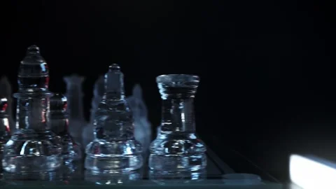 Low-angle close-up camera motion panning horizontally past glowing glass chess p Video stock 347189802