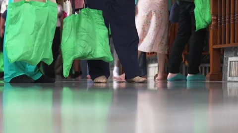 Low angle close up of a crowd of barefoot tourists inside a Buddhist Temple is Stock Footage 289805132
