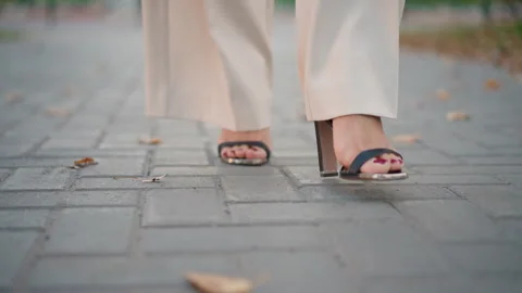 Low angle close up of feet in heeled sandals walking forward on textured Stock Footage 347543955