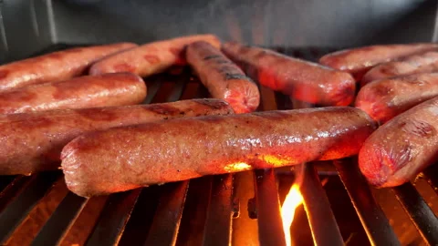Low angle close-up grilling oversized hot dogs on outside grill Stockbeeldmateriaal 337576160